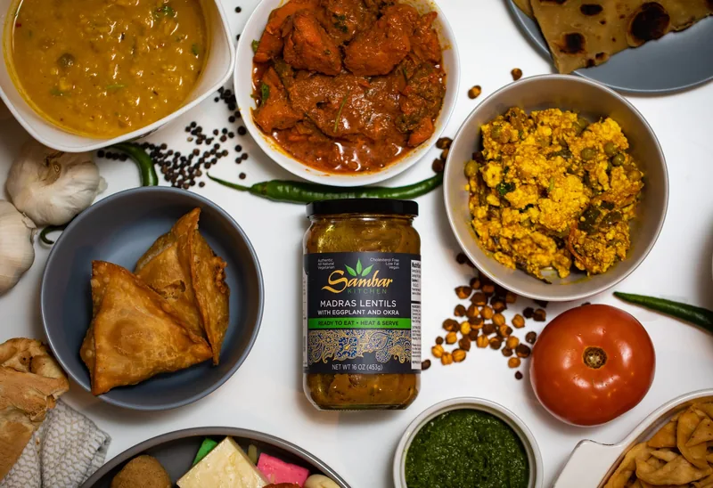 An overhead spread of Indian dishes around a jar of Sambar Kitchen Madras Lentils